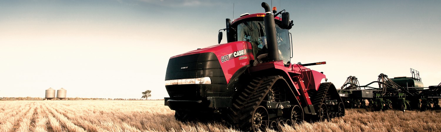 Case IH Steiger Series in a sunny golden hay field pulling an attachment.